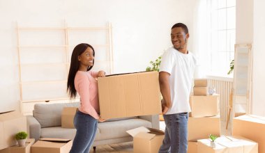 Sevgi dolu siyah çift, karton kutuları birlikte taşıyorlar, taşınma gününde birbirlerine yardım ediyorlar. Afro-Amerikalı kiracıların eşyaları yeni bir daireye taşınıyor, panorama