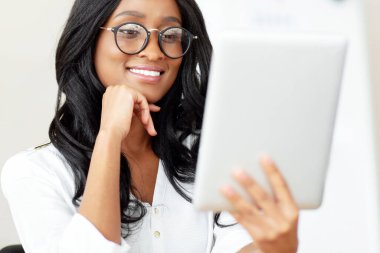 Tablet bilgisayar kullanan mutlu zenci iş kadınının portresi, video görüşmesi yapmak, ofisteki meslektaşımla sohbet etmek. Genç Afrikalı Amerikalı girişimci iş dünyasından.
