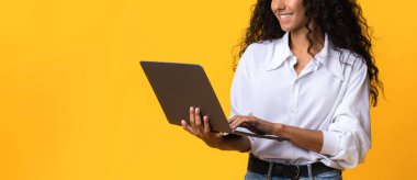 Uzaktan kumanda. Gülümseyen Genç Serbest Kadın Laptop Kullanıyor, Bilgisayarda İnternet 'e göz gezdiriyor, İnternette İş Yapıyor, Milenyum Kadını Mesafeden Hoşlanıyor, Sarı Arkaplanda Duruyor, Boşluğu Kopyala