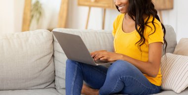 Güzel siyahi bayan evde çalışıyor ya da çalışıyor, dizüstü bilgisayar kullanıyor. Güzel Afrikalı Amerikalı blogcu, modern cihaz ile blogunda yeni bir yazı yazıyor.