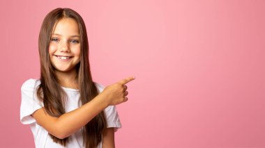 Vay canına, harika. Sırtında parmak ile gülümseyen küçük çocuk işaretleri, boş alana ve pembe arka planda izole edilmiş ürünleri sunar.