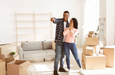 Siyah milenyum adamı heyecanlı kız arkadaşına yeni evlerinde bir şey gösteriyor, fotokopi odası. Gülümseyen Afro-Amerikalı adam mobilya koyacağı yeri işaret ediyor. Taşınma günü konsepti