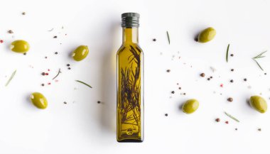 Şişede otlar ile zeytinyağı, beyaz arka plan üzerinde dağınık zeytin ve biberiye, üst görünümü. Gıda arka plan konsepti