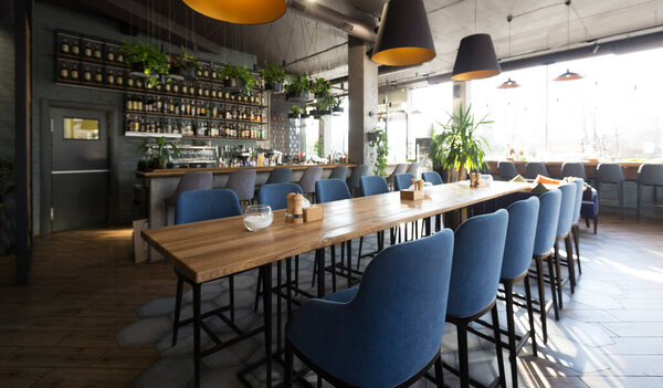 Open wooden bar counter with alcohol on shelves in modern cafe, restaurant interior, panorama, copy space