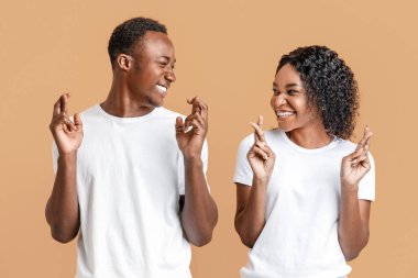 Sevgi dolu bir dilek. Genç, neşeli, Afro-Amerikalı çift parmaklarını çapraz yapıp gülümsüyor, sarı stüdyo geçmişleri var. Duygusal siyah erkek ve kadın iyilik için dua ediyorlar.