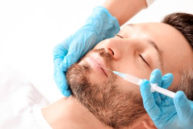 Sakallı adamın estetik kliniğinde burun enjeksiyonu yaptırırken, fotokopi odasında. Estetik cerrah yakışıklı bir adamın yüzüne yaşlanma önleyici iğne yapıyor. Erkek kozmetolojisi, estetik tıp konsepti