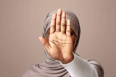 Ayrımcılık yok. Tanımlanamayan siyahi kadın tesettürde kameraya el hareketlerini gösteriyor. Eli başörtülü Afrikalı Müslüman kadın, açık arkaplanda poz veriyor.