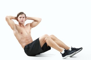 Seksi vücutlu atletik genç bir adam stüdyo arka planında karın kasları egzersizi yapıyor, panorama. Bin yıllık vücut geliştiricisinin tam uzunluğu vücut kaslarını çalıştırıyor.