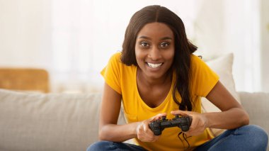 Evde eğleniyorum. Çevrimiçi video oyunları oynayan mutlu siyahi kadın, panorama. Heyecanlı Afrikalı Amerikalı kadın joystick ile çevrimiçi bilgisayar oyunu oynuyor.