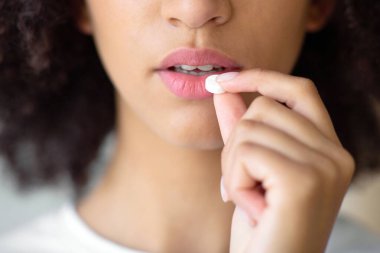 Baş ağrısından, mide ağrısından, vitamin almaktan, sakinleştirici ilaçlardan, sağlık hizmetlerinden. Üzücü bin yıllık çekici sakin Afrikalı Amerikalı kadın ağrı kesici ya da vitamin alıyor, yakın çekim, boş alan, kesilmiş