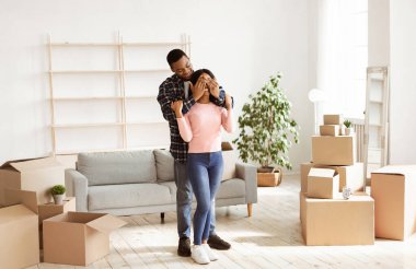 Taşınma günü konsepti. Milenyum Siyahi Adam, kız arkadaşlarının gözlerini karton kutularla kapatıyor. Afrikalı Amerikalı adam yeni dairesinde sevgili karısına sürpriz yapıyor.