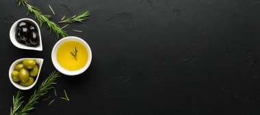 Zeytinyağı, taze zeytin ve biberiye filizi kompozisyonu siyah arka plan, üst görünüm, kopyalama alanı
