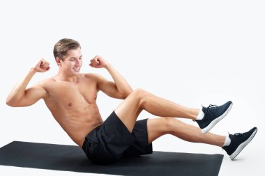 Genç ve güçlü bir adam spor minderi üzerinde egzersiz yapıyor, arka planda karın kasları üzerinde çalışıyor, fotokopi çekiyor. Çekirdek egzersizi yapan çıplak gövdeli yakışıklı bir milenyum sporcusu. Etkin yaşam tarzı kavramı