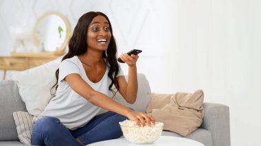 Genç siyahi kadın boş zamanlarını televizyon izleyerek ve evdeki kanepede patlamış mısır yiyerek geçiriyor. Uzaktan kumandalı güzel Afrikalı Amerikalı kadın oturma odasında ilginç bir film izliyor.