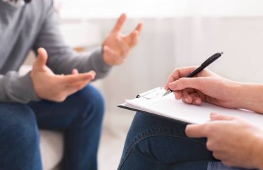 Psikoterapist notlar yazıyor, terapi seansında duygusal bir hastaya teşhis koyuyor, boş alan yaratıyor.