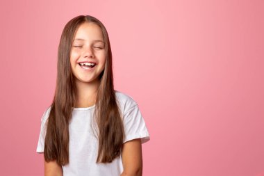 Eğlen, eğlen, eğlen. Gülümseyen çocuk ağzı açık ve gözleri kapalı, pembe arka planda izole edilmiş, stüdyo çekimlerinde.