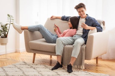 Çinli genç çift telefonlarını internete takıyor ve hafta sonları evde koltukta oturup mesajlaşıyorlar. Cep telefonu, Modern Gadget Yaşam Biçimi Uygulaması