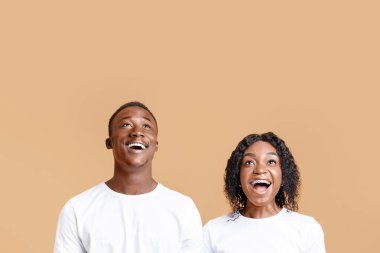 Heyecanlı siyah çift sarı stüdyo arkaplanından fotokopi alanına bakıyor. Afro-Amerikan erkek ve kadın reklamları izliyor ya da sezonluk satışlar hakkında duyuru yapıyor.