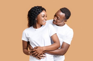 Mutlu Afrikalı genç Amerikalı adam gülümseyen kız arkadaşına sarılıyor, birlikte poz veriyor, mekanı kopyalıyor. Aşk, ilişki kavramı. Sarı arka planda kucaklaşan ve gülümseyen neşeli siyah çift