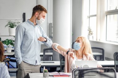 Yeni normal ve birlikte çalışıyoruz. Dost canlısı bin yıllık meslektaşlar sosyal mesafeyi koruyorlar, birbirlerini dirseklerle selamlıyorlar, koronavirüs enfeksiyonunun yayılmasını önlüyorlar.