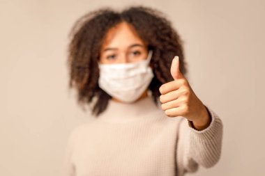 Koronavirüs ve gripte koruma, karantinadan sonra yeni bir normal. Krem rengi arka plan, boş yer ve stüdyo çekimlerinde izole edilmiş koruyucu maskeli genç Afro-Amerikan kadınlarına odaklan.
