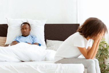 Hüsrana uğramış kadın ilişki sorunları ve ağlama hakkında düşünüyor, düşünceli çift üstüne kavga ediyor, üzgün aşıklar ayrılmayı düşünüyor. Üzgün Afrikalı Amerikalı kadın yatakta oturduğu için hayal kırıklığına uğramış bir adam.