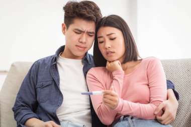Ebeveyn olmayı hayal eden çift. Üzgün Asyalı Eşler Olumsuz Hamilelik Testi Tutuyor Evde Depresyonda Oturuyorlar. Çocuk Doğum Sorunu, Aile Zorluğu Kısırlık Konsepti.