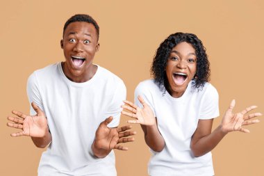 Hayret verici siyahi çift avuçlarını gösteriyor, avuçlarını gösteriyor, şaşkınlık, mutluluk ve başarıyı ifade ediyorlar. Afrikalı Amerikalı duygusal erkek ve kadın sarı stüdyo arka planında el kol hareketi yapıyorlar.