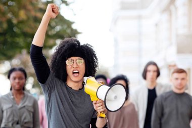 Karışık ırk adamıyla megafonlu önde gelen uluslararası protestocu grubu, yumruklarını kaldırıp sloganlar atıyorlar. Hoparlörlü grevcilerin lideri hükümete seslendi, boşluğu kopyala