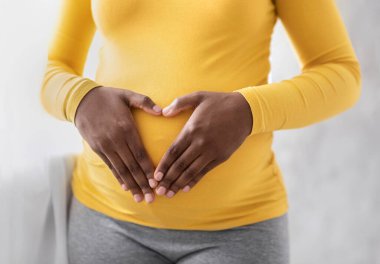 Karnında avuçlarını kırbaçlayan, kalp şeklinde avuç içi tutan hamile bir zenci kadın. Tanımlanamayan Afro-Amerikalı bir bayan pencerenin önünde bekliyor. Hamilelik ve annelik kavramı