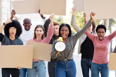 Uluslararası grup genç göstericileri ellerinde megafon ve boş pankartlarla sokağa saldırıyor. Dışarıda protesto eden, insan haklarını savunan, boş pankartlı çok ırklı öğrencilerden oluşan bir grup.