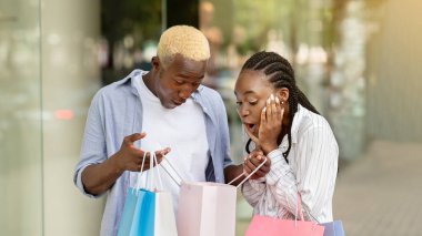 Omg, bu tam da istediğim şey. Duygularını ifade ediyor. Mutluluk. Afro-Amerikalı bir adam alışveriş torbalarıyla dükkan penceresinin yakınındaki bir kıza bedava alan gösteriyor.