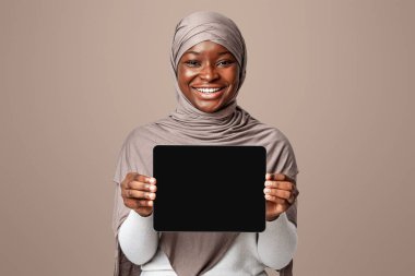 Siyah Ekran ile dijital tablet tutan gülümseyen Afrikalı Müslüman kadın, tesettürlü İslami Kadın, Işık Arkaplan Arkaplanında Uygulama Tasarımı ya da Web siteniz için Kopyalama Alanı ile tebeşir gösterimi