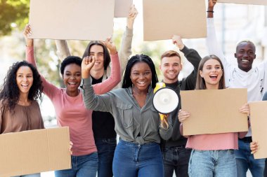 Boş pankartlarla gezen neşeli çok ırklı öğrenci grubu aktif protestoculara öncülük eden karizmatik Afrikalı Amerikalı genç kadın ırkçılığa ve ayrımcılığa karşı sloganlar atıyorlar.