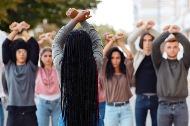 Tanımlanamayan uzun saçlı siyahi kadın insan hakları için grev yapan protestocuların lideri, çok ırklı göstericilerin önünde el ele tutuşan ve yumruklarını kaldıran kadınların arka planı.