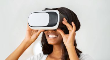 Günlük yaşamda gelecek teknolojileri. VR kulaklık takan mutlu siyah bayan ve evde siber uzay keşiflerinin tadını çıkarıyor. Afro-Amerikalı kadın sanal gerçekliğe gömüldü