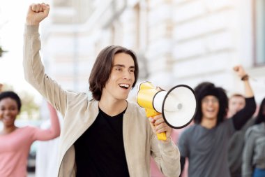 Sokakta megafonlu karizmatik bir eylemci sloganlar atıp yumruğunu kaldıran, uluslararası göstericileri yöneten beyaz bir genç kilit altına alma kurallarına karşı geliyor.