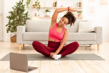 Siyah fitness kızı laptopta egzersiz yapıyor evde online antrenman yapıyor. Formda Kalın Konsepti