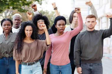 İklim değişikliği protesto konsepti. Uluslararası gençlerden oluşan bir grup sokakta grev yapıyor, sloganlar atıyorlar ve yumruklarını kaldırıyorlar, devletin gezegeni kurtarmasını istiyorlar, kirliliği azaltıyorlar.