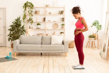 Kilo kaybı sorunu. Mutsuz Afrika kökenli Amerikalı kadın kilolarının üzerinde duruyor ve şişko göbeğine dokunuyor. Aşırı Kilo Vermek, Obeziteyle Mücadele Konsepti değil. Metin için Boşluğu Kopyala, Tam Uzunluk