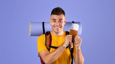 Sırt çantalı mutlu genç adam mavi stüdyo geçmişinde uluslararası pasaport ve uçak biletleri gösteriyor. Milenyum yolcusu yurt dışına tatile çıkmaya hazır.