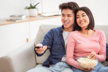 Çinli bir çift uzaktan kumandalı televizyon kanallarını değiştiriyor, hafta sonunu birlikte evde koltukta oturarak geçiriyorlar. Asyalı Eşler Sinema ve Patlamış Mısırdan Hoşlanıyor