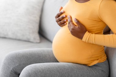 Genç siyahi hamile bir kadın göğsünde acı hissediyor, kendine masaj yapıyor, boş yer var. Tanımlanamayan Afrikalı kadının göğüslerine dokunmasını bekliyor. Oturma odasında kanepede oturuyor.