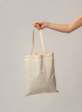 Kadın elinin boş Eko Tuval Taşıması, Tanınmayan Kadın, Plastik Atık Kullanmadan Sürdürülebilir Alışverişin Keyfi, Açık Gri Stüdyo Arkaplanının Üzerinde Durmak, Boşluğu Kopyalamak