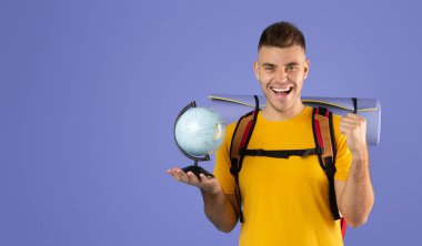 Neşeli genç gezgin mavi arka planda EVET hareketi yapıyor