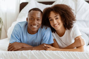 Genç, sevimli, gülümseyen bir çift yatakta. Covid-19 tecridi sırasında popüler ev blogcuları. Mutlu yıllar Afro-Amerikan karı-koca. Sabahları rahat yatak odasında kameraya bakıp uzayı kopyalıyorlar.