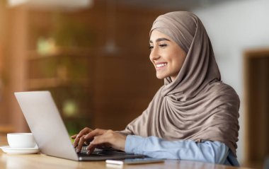 Mutlu Arap kadın müşterilerle laptopta sohbet ediyor, kafede oturuyor, boş bir alanda.