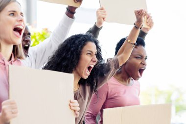 Sokakta boş afişleri olan uluslararası genç gösterici grubuna yakın çekim. Boş slogan tahtaları olan duygusal grevciler bağırıyor, yumruklarını kaldırıyor, insan hakları için mücadele ediyorlar.