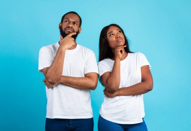 Düşünceli Afrikalı Amerikalı bir çiftin portresi. Düşünen, bakan, dokunan, mavi stüdyo arka planında tek başına duran. Düşünceli siyah erkek ve kadın karar veriyor.
