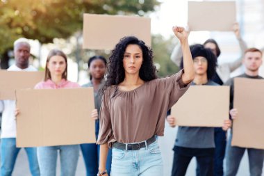 Sokaktaki bir grup göstericiye liderlik eden aktif, güzel bir genç kadın. İnsan ya da hayvan haklarını ve ırkçılığı protesto eden boş pankartlı uluslararası çeşitli insanlar.